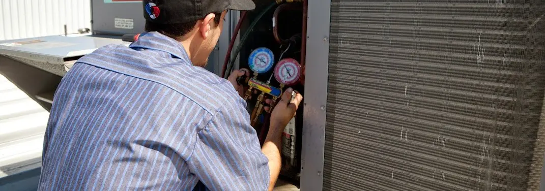 HVAC technician servicing a condenser unit in Kansas City